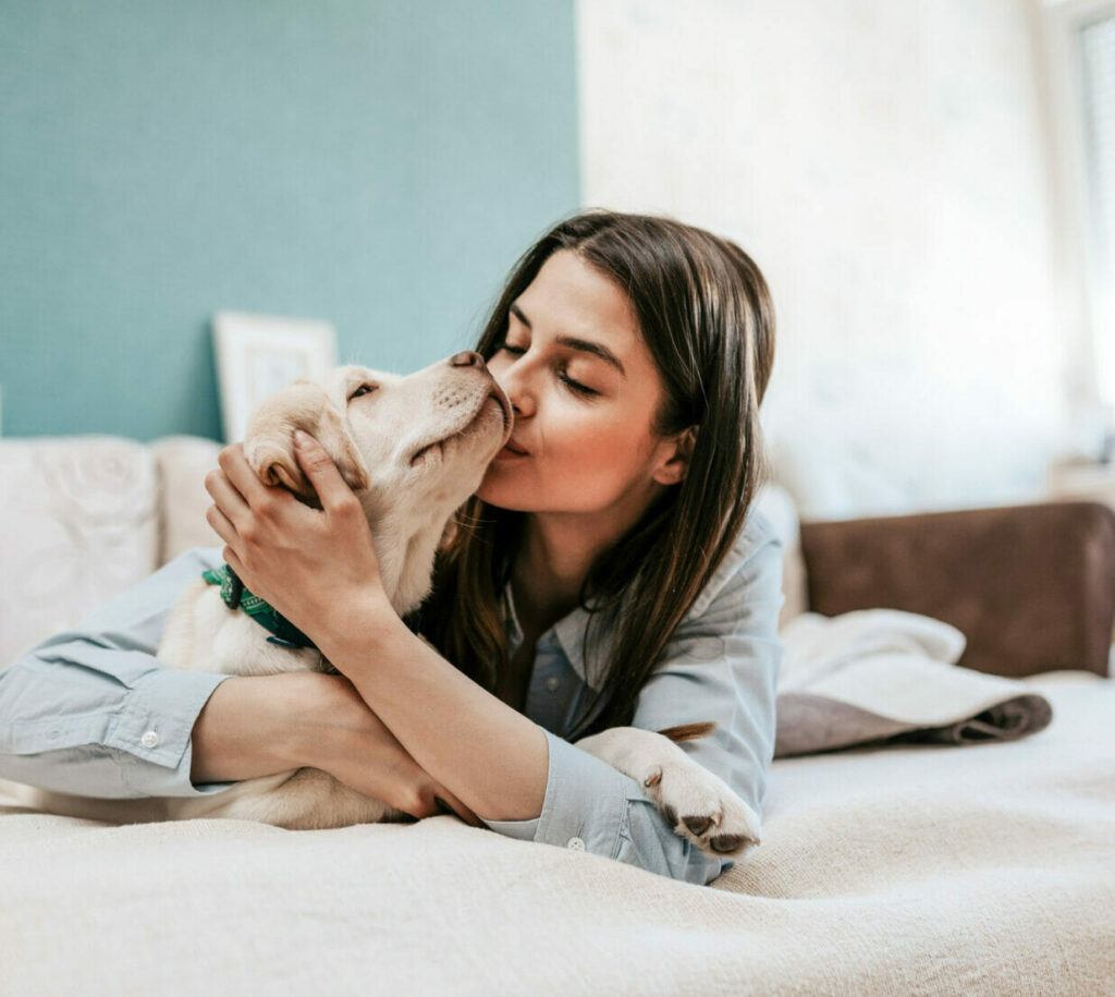 Girl kissing dog on bed